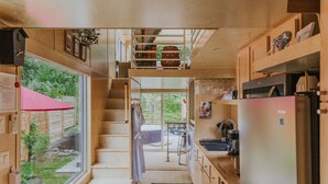 Une cuisine compacte donnant sur le jardin, un petit coin repas et un escalier menant à l’étage supérieur.