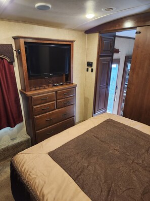 Cozy retreat with a bed, dresser, and flat-screen TV, offering a comfortable space to unwind.