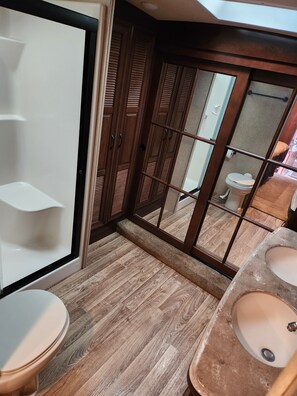 Bathroom features a toilet, sink, and shower area.