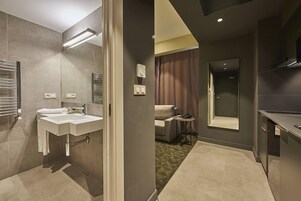 Un baño moderno con lavamanos dobles, un espejo, toalleros y una zona de ducha.
