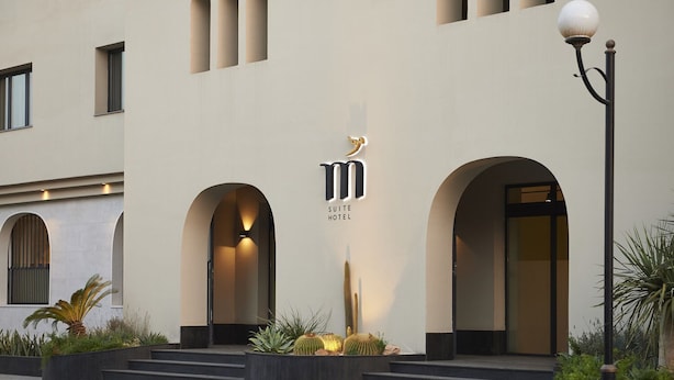 A modern hotel entrance with a minimalist design, featuring a prominent logo and a well-lit archway. - M Suite Hotel (Algiers)