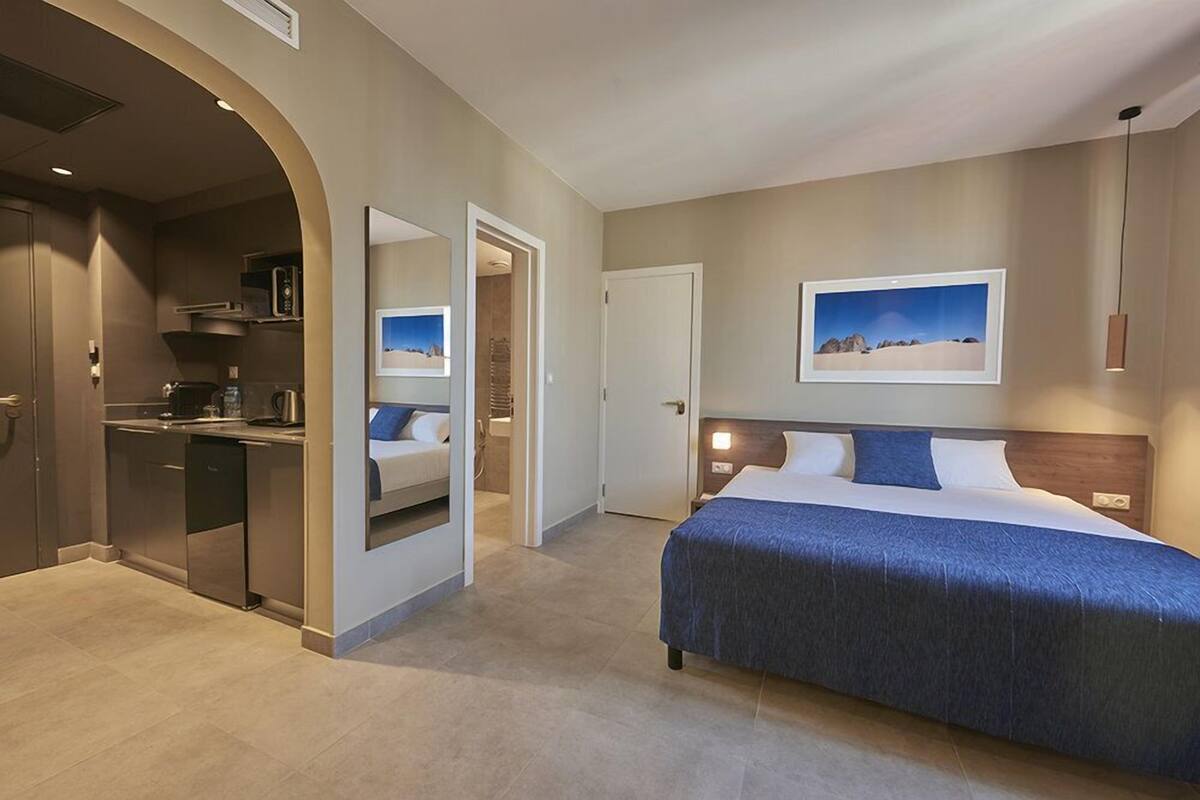 Una habitación de hotel moderna con cama, escritorio y kitchenette.