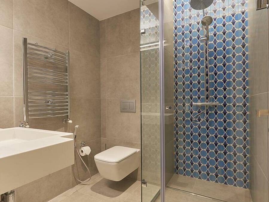 A modern bathroom with a glass-enclosed shower, a white sink, and a toilet.