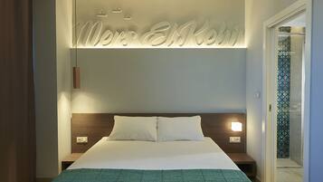 Una habitación de hotel moderna con una cama grande, un cabecero con luz y un cartel en la pared.