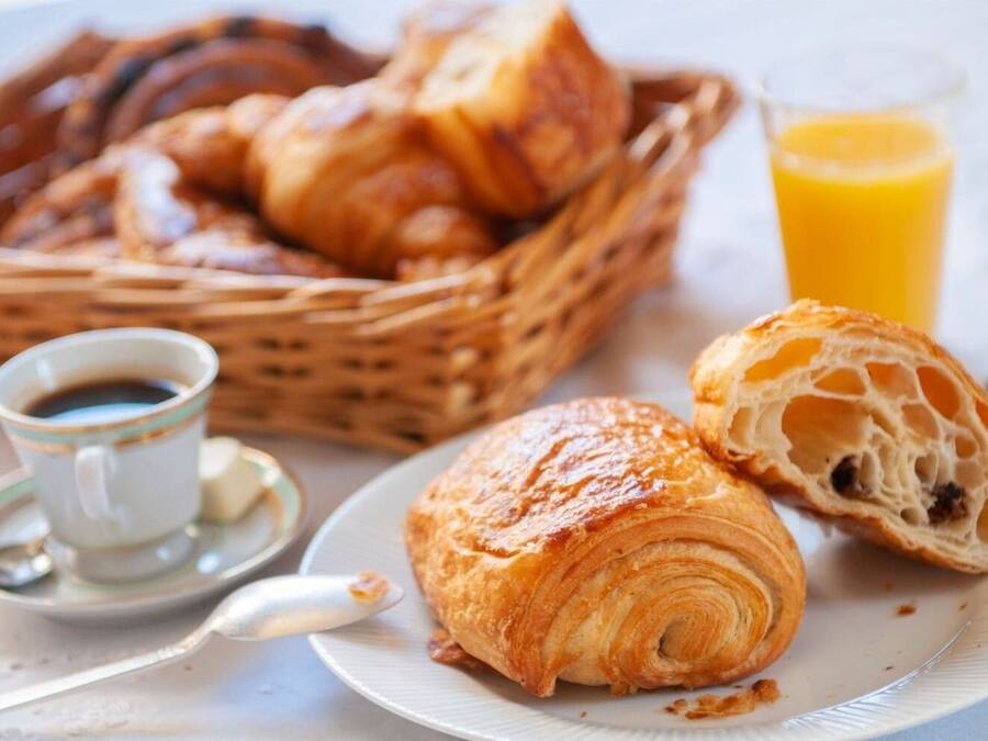 Un desayuno con croissants, un vaso de zumo de naranja y una taza de café.