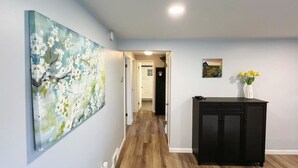 Ein Korridor mit Holzboden, einem schwarzen Schrank und einem Gemälde an der Wand.