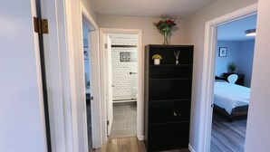 Ein Flur mit einer schwarzen Regaleinheit, einer weißen Tür und einem Bett im angrenzenden Zimmer.