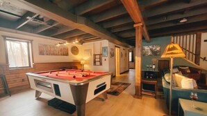 Een pooltafel in een ruimte met houten vloeren en zichtbare balken.