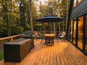 A wooden deck with outdoor furniture, including a table and chairs, and a grill.