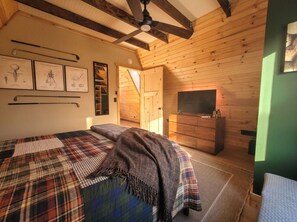 A cozy room with a bed, a wooden dresser, and a television. - Gorgeous New A-Frame w/ Sauna & Gameroom - Minutes to Pools, Golf and Skiing (Bellaire)