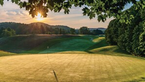 Een golfbaan met een duidelijke route, omringd door bomen en heuvels.