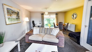 Een moderne woonkamer met een bank, een salontafel, een lamp en een lijst met een stadsgezicht aan de muur.