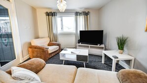 Een moderne woonkamer met een bank, een salontafel, een televisie en een kroonluchter.