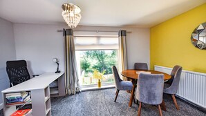 Een moderne kamer met een eettafel, stoelen, een bureau en een boekenkast.
