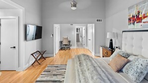 A modern bedroom with a large bed, a television, and a painting on the wall.
