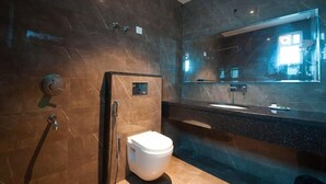 A modern bathroom with a marble wall, a toilet, a sink, and a large mirror. - Hotel Bonito- Delhi IGI Airport (New Delhi)