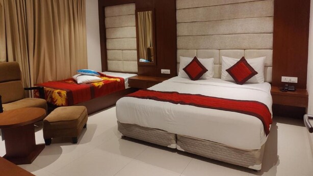 A hotel room with a large bed, a smaller bed, a sofa, a chair, and a nightstand with a phone. - Hotel Bonito- Delhi IGI Airport (New Delhi)