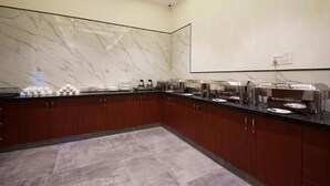 A modern kitchen with marble backsplash, stainless steel appliances, and a buffet setup. - Hotel Bonito- Delhi IGI Airport (New Delhi)