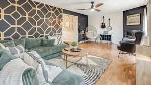 Una sala de estar moderna con un sofá seccional, una mesa de centro, un ventilador de techo y una chimenea.