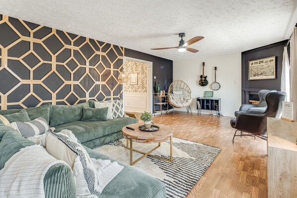 A modern living room with a sectional sofa, a coffee table, a ceiling fan, and a fireplace. - Mtn House w/ Hot Tub · Sauna · Arcade & Theater (Leicester)