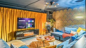 Una sala de estar con un televisor de pantalla plana grande, un sofá, una mesa de centro y una pared con diseño.