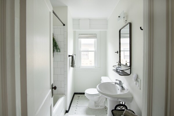 A compact bathroom with a toilet, sink, and shower.