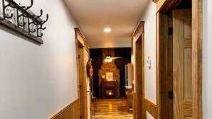 Un couloir doté d’un plancher en bois, d’un porte-manteau fixé au mur et d’une cheminée au fond.