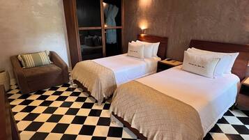 A hotel room with two beds, a checkered floor, a sofa, and a wardrobe.