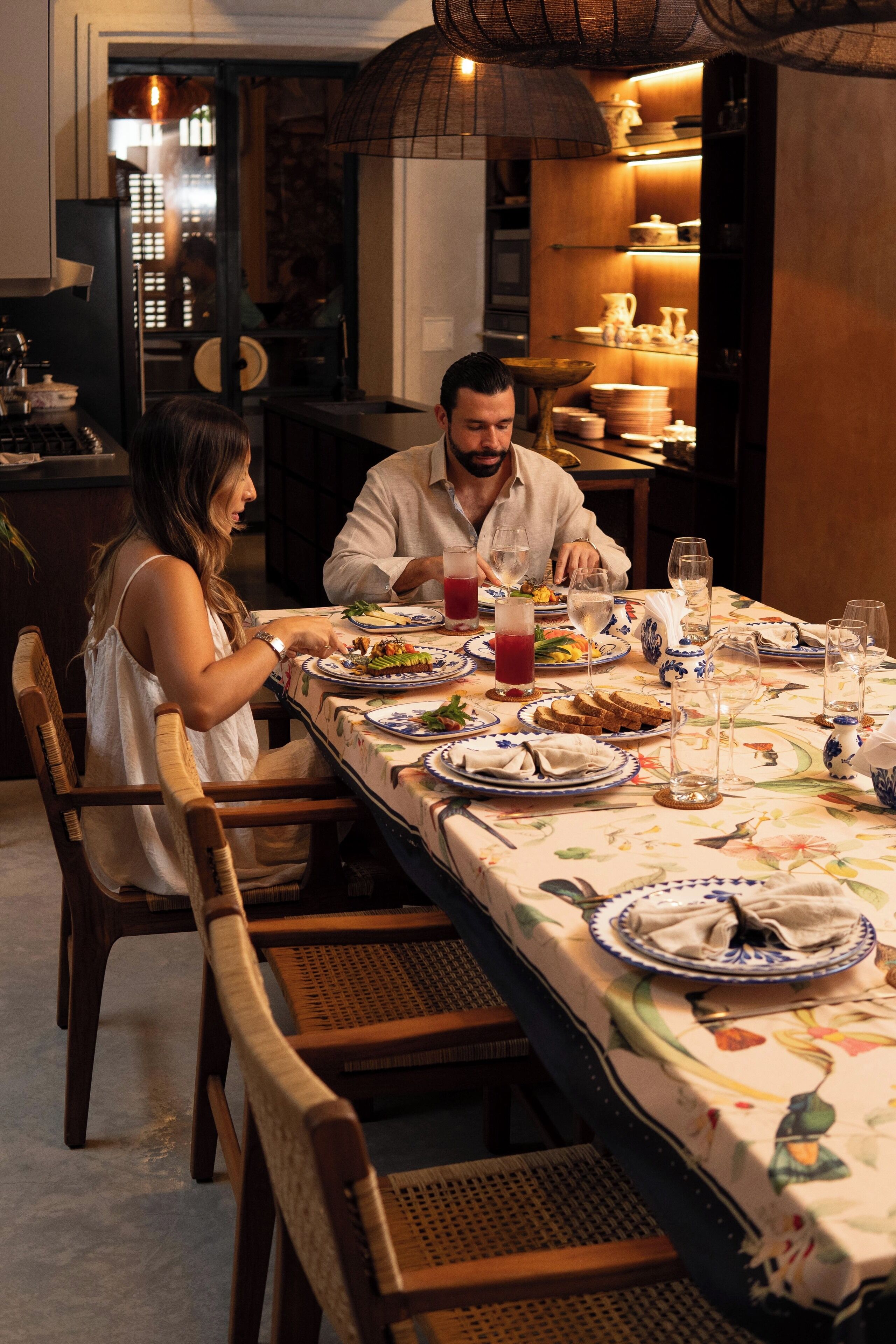 Una mesa de comedor servida con platos, vasos y una jarra de bebida roja.