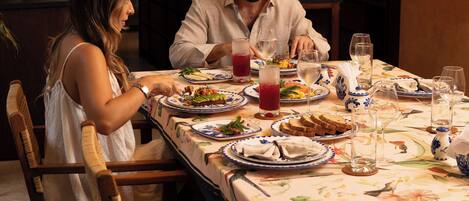 Una mesa de comedor servida con platos, vasos y una jarra de bebida roja.