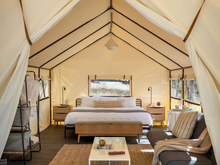 Acomodação em tenda com uma cama, um sofá, uma mesa de centro e uma mesa lateral.