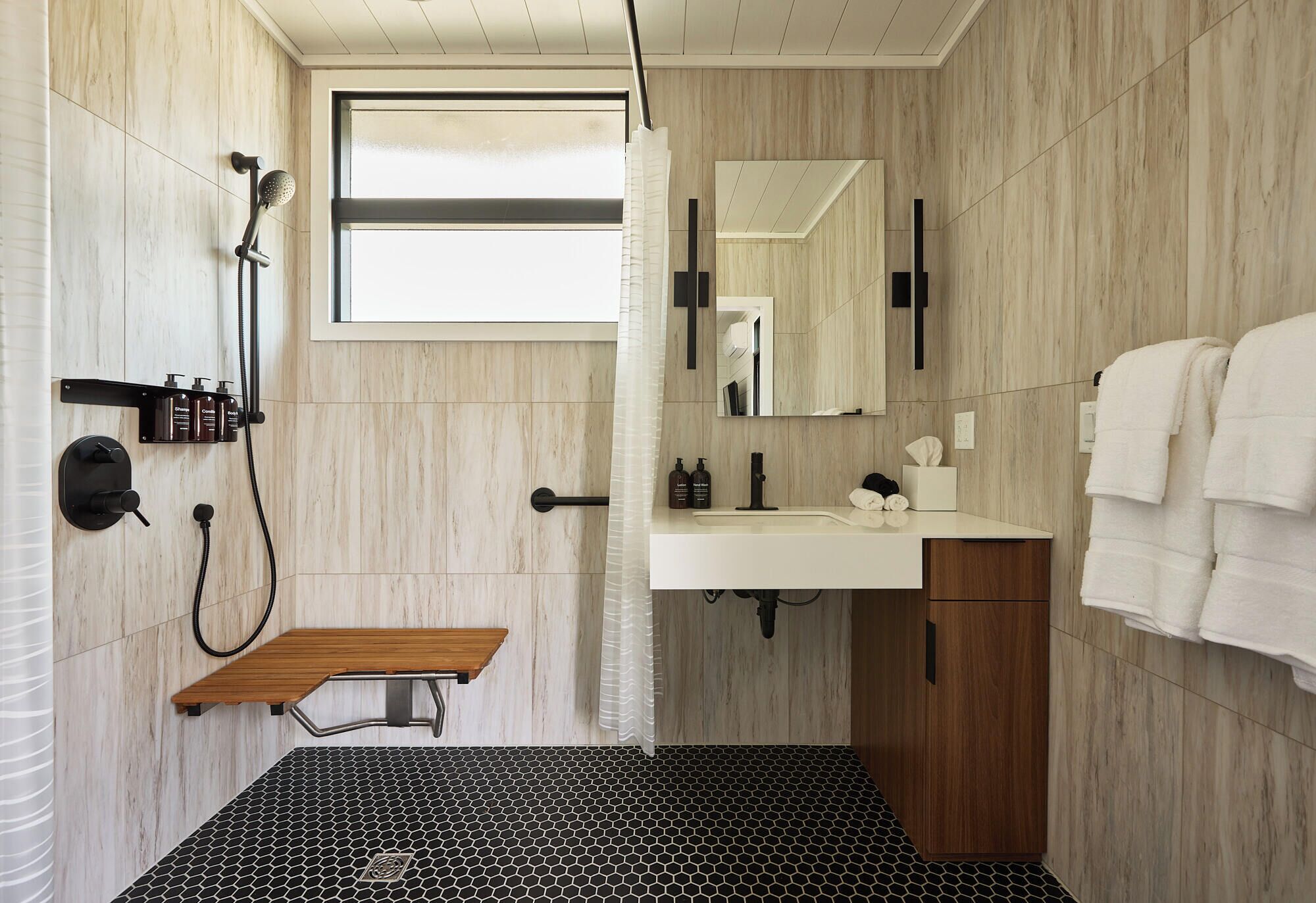 Une salle de bain moderne avec une douche, un lavabo et un banc en bois.