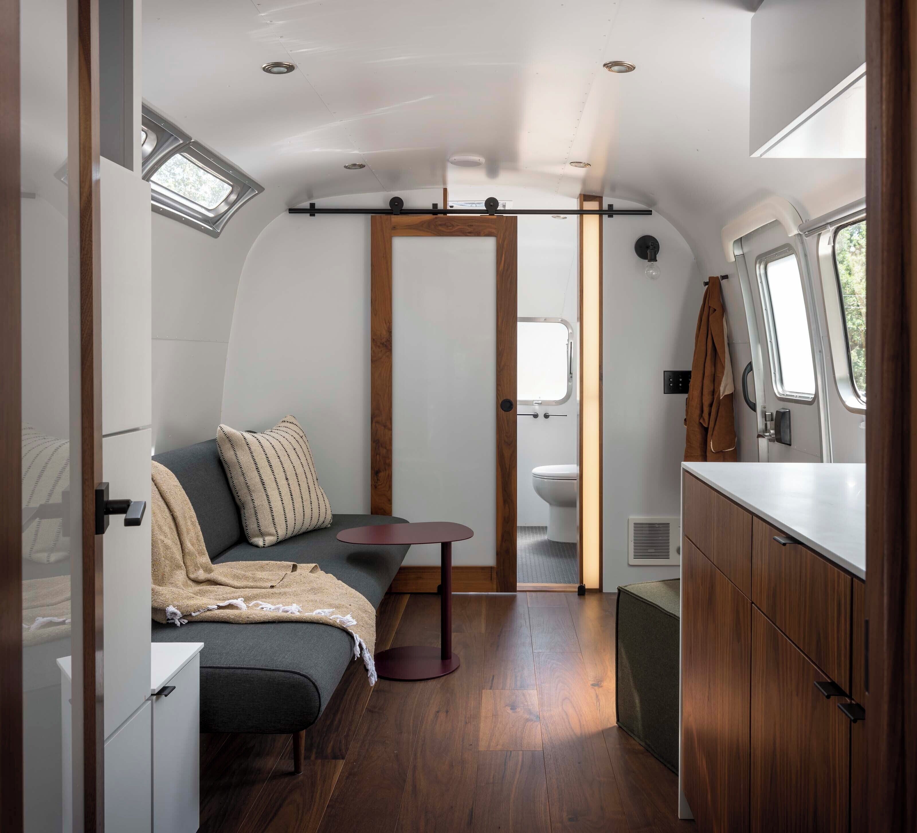 A compact, well-lit interior with a seating area, kitchenette, and a small bathroom.
