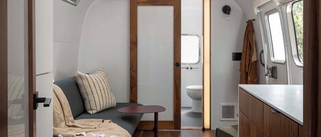 A compact, well-lit interior with a seating area, kitchenette, and a small bathroom.
