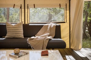 A cozy room with a sofa, a table, and a window overlooking a forest.