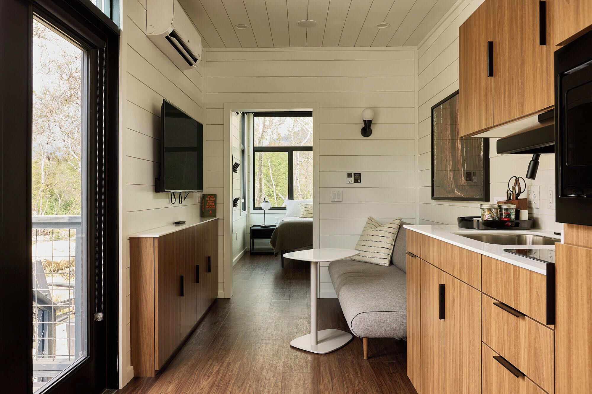 A modern kitchen with wooden cabinets, a central island, and a dining area with a sofa.