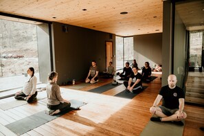 A yoga class in a room with wooden floors and large windows.