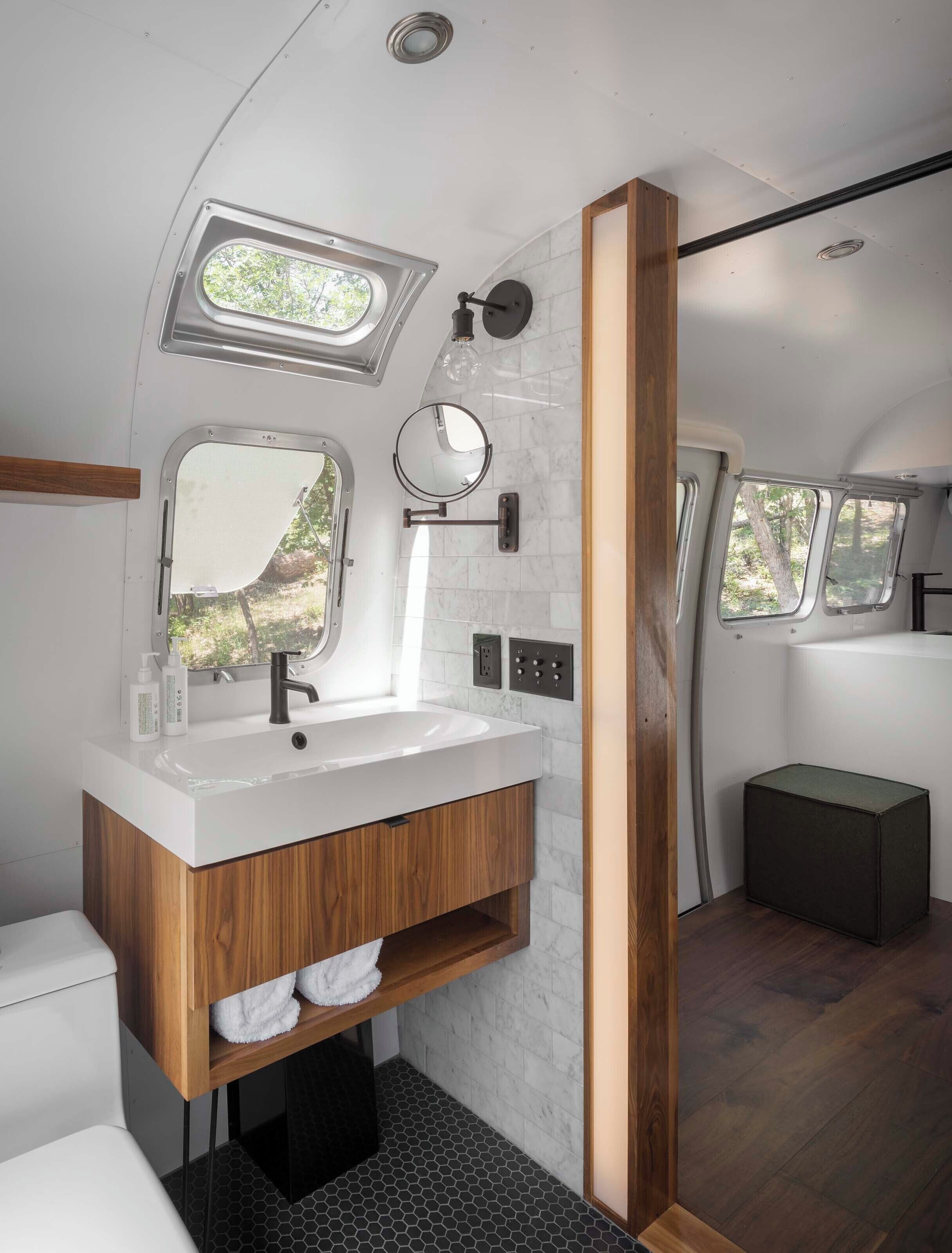 A modern bathroom with a vanity, sink, mirror, and a window providing natural light.