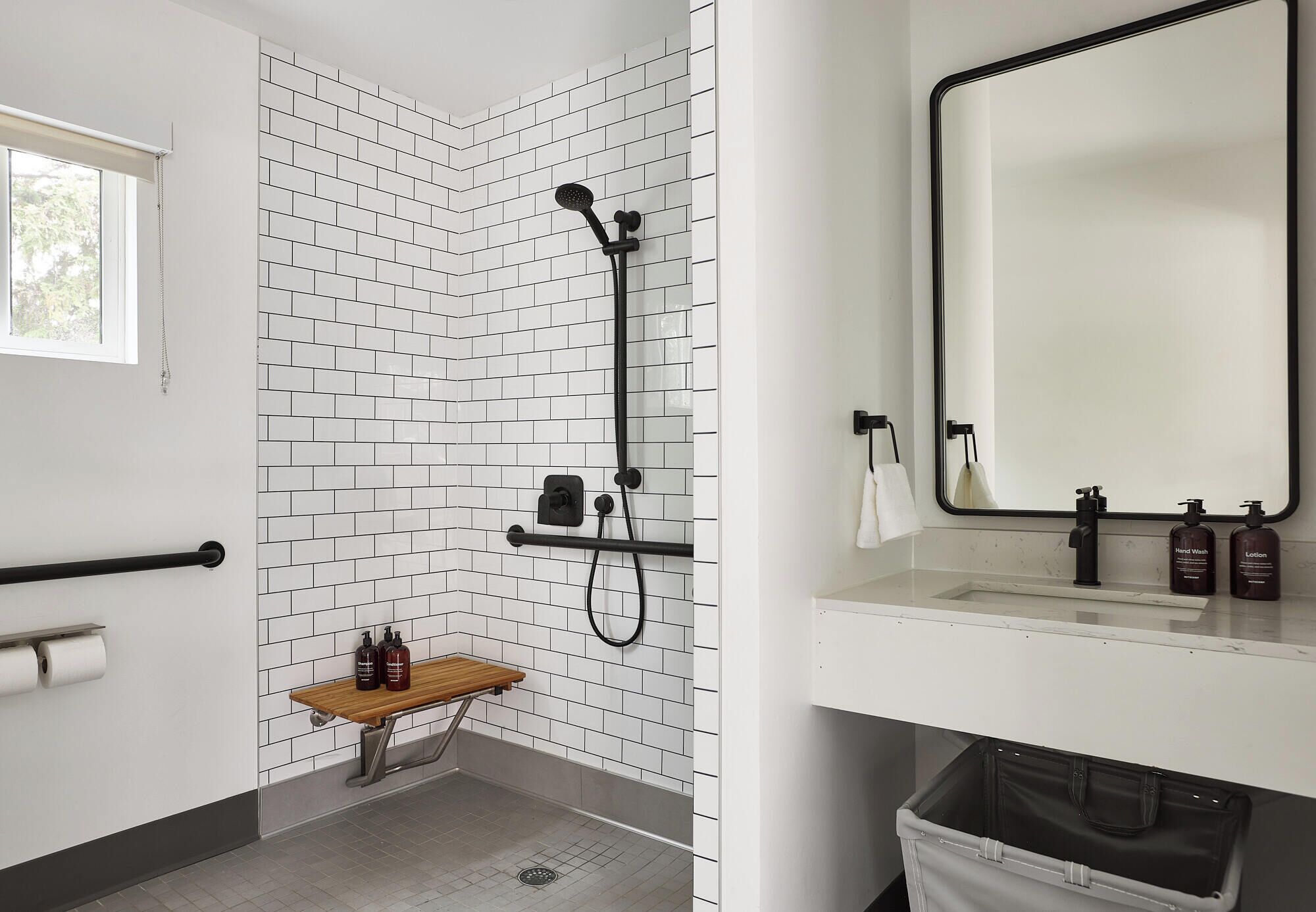 Une salle de bain équipée d’une douche, de papier toilette, d’un banc et d’un lavabo avec des articles de toilette.