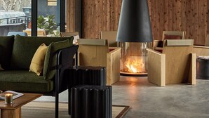 A modern living room with a large fireplace, wooden walls, and a green sofa. - AutoCamp Sequoia (Three Rivers)