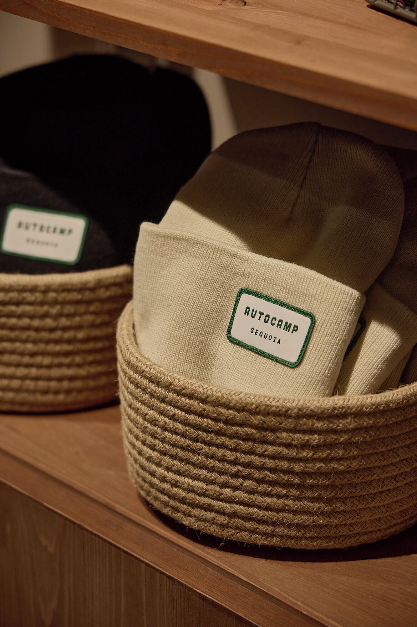A shelf with woven baskets containing hats labeled 'AUTOCAMP SEQUOIA'.