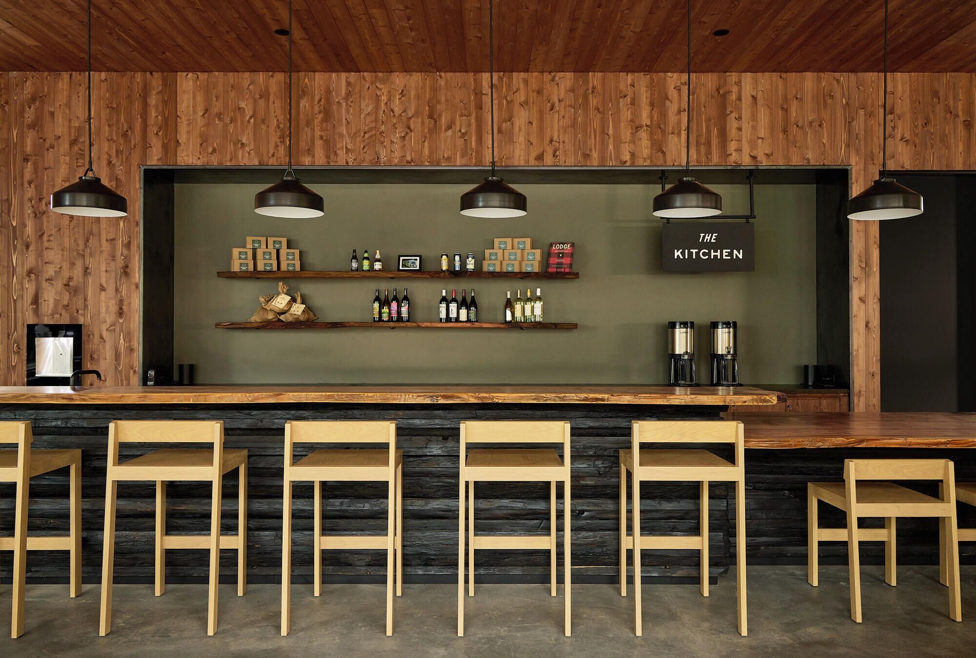 A bar area with wooden chairs, shelves with bottles, and a sign reading "THE KITCHEN".