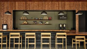 A bar area with wooden chairs, shelves with bottles, and a sign reading "THE KITCHEN".