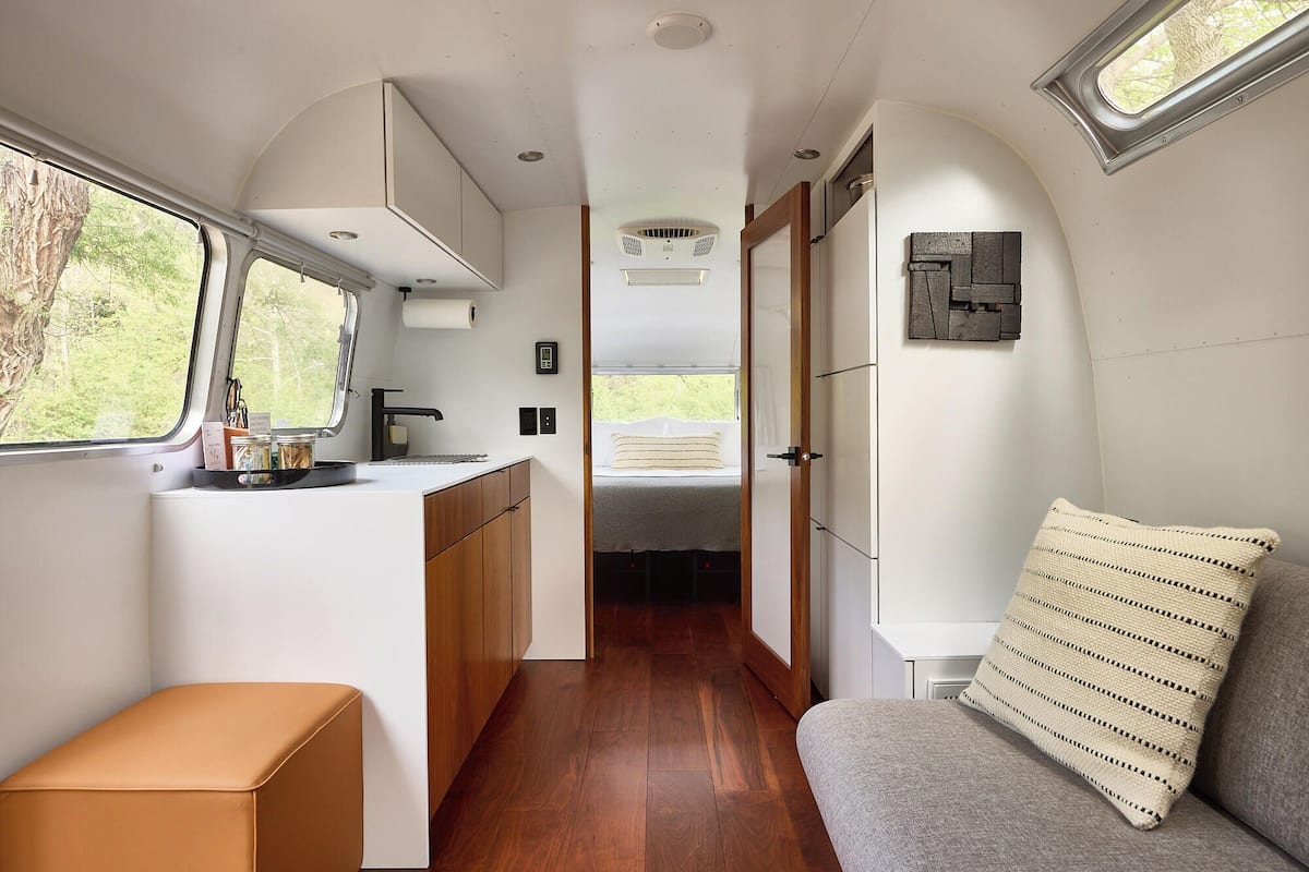 Interior compacto de una autocaravana, con kitchenette, zona de descanso y baño pequeño.
