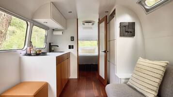 Ein kompaktes Wohnmobil-Interieur mit Küchenzeile, Schlafbereich und kleinem Badezimmer.