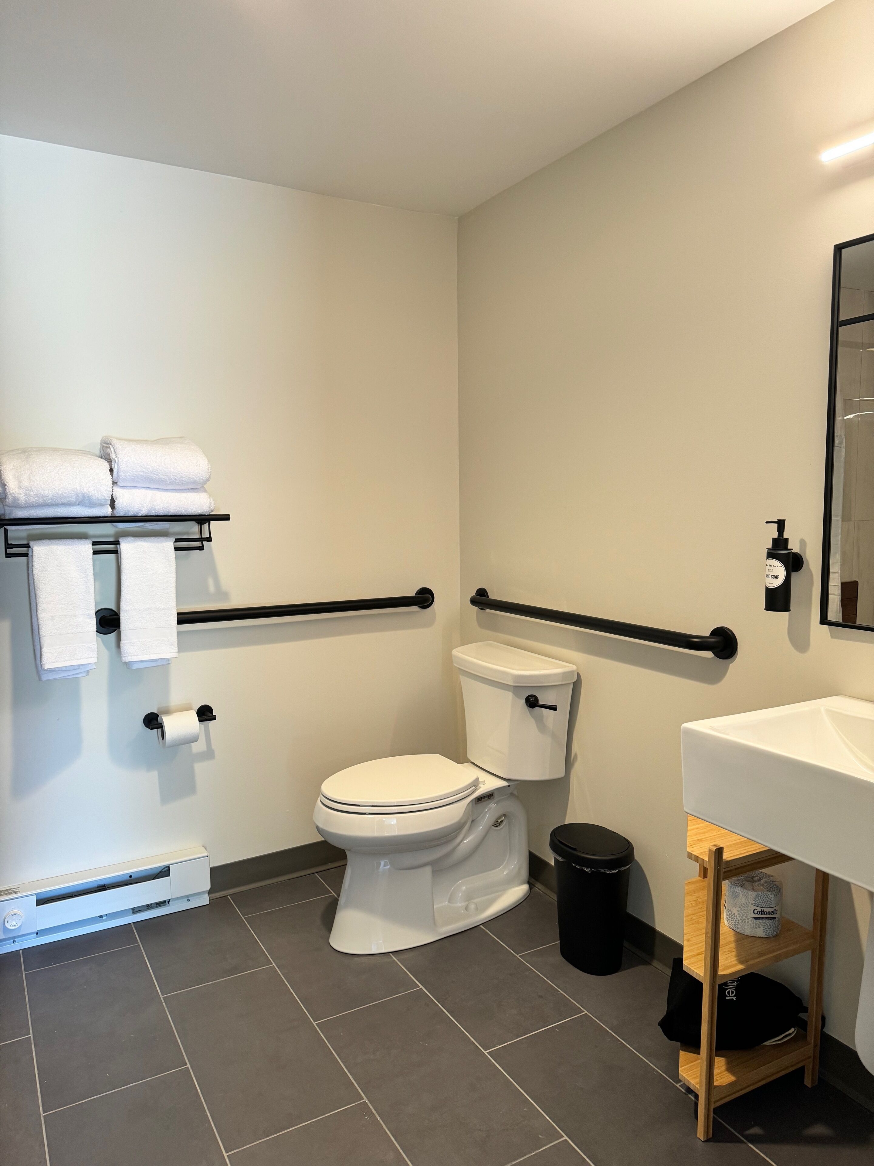 Ein Badezimmer mit Toilette, Waschbecken, Handtuchhalter, einem Fön und einem Mülleimer.