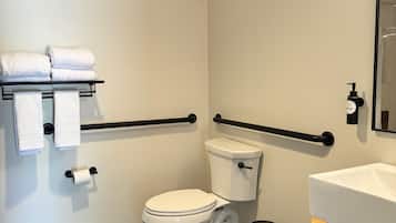 Ein Badezimmer mit Toilette, Waschbecken, Handtuchhalter, einem Fön und einem Mülleimer.
