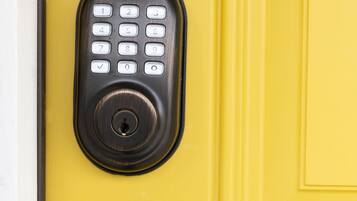 A Yale keypad lock on a yellow door.