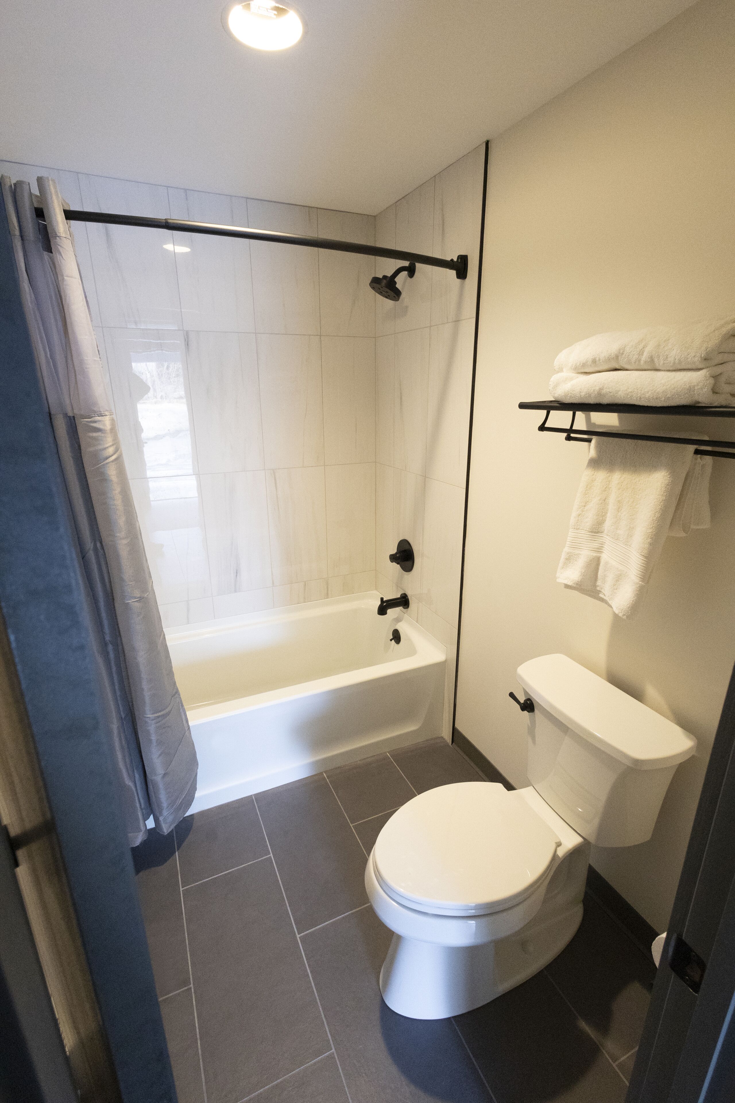 A modern bathroom with a bathtub, toilet, and shower curtain.
