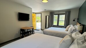 A hotel room with two beds, a desk, a TV, and a window with curtains. - East Rock Inn (Great Barrington)